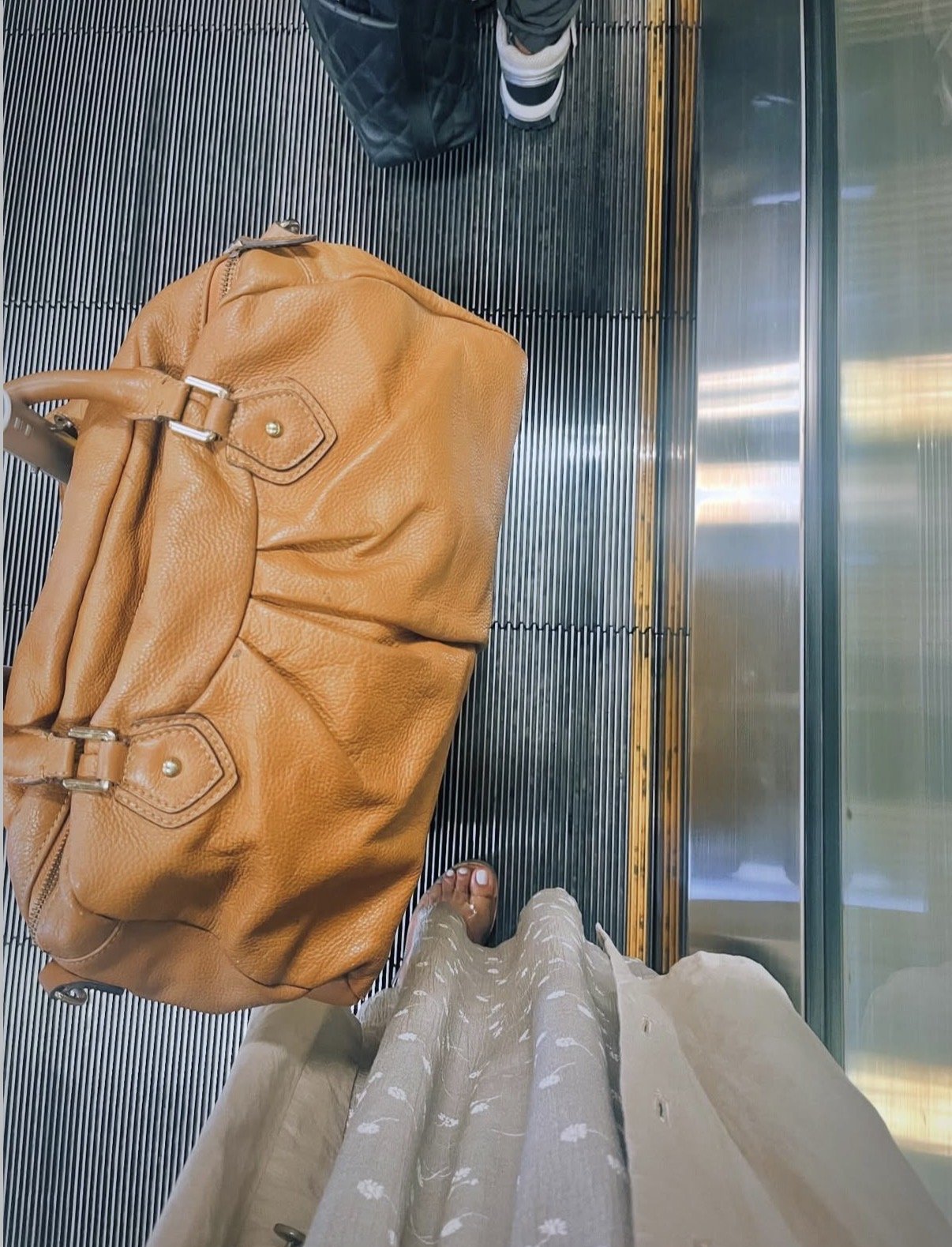 Tan handbag on a glass-paneled escalator