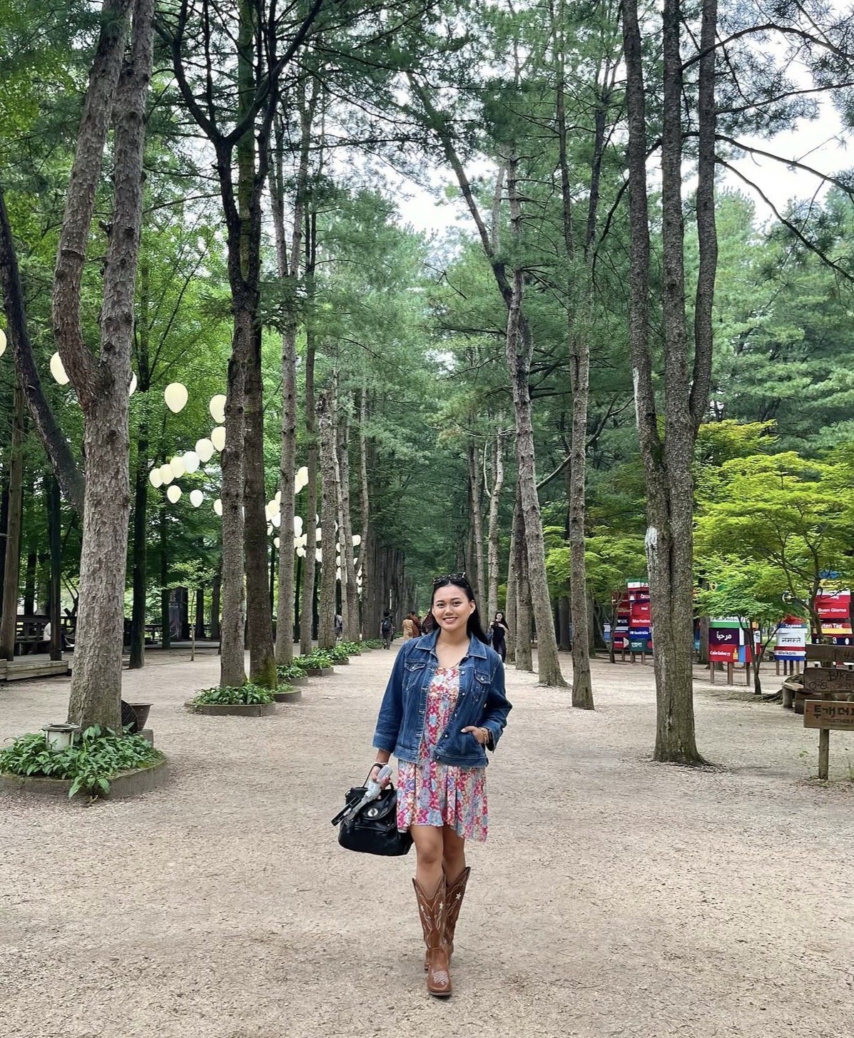 Angie on a tree-lined walkway with paper lanterns at Nami Island