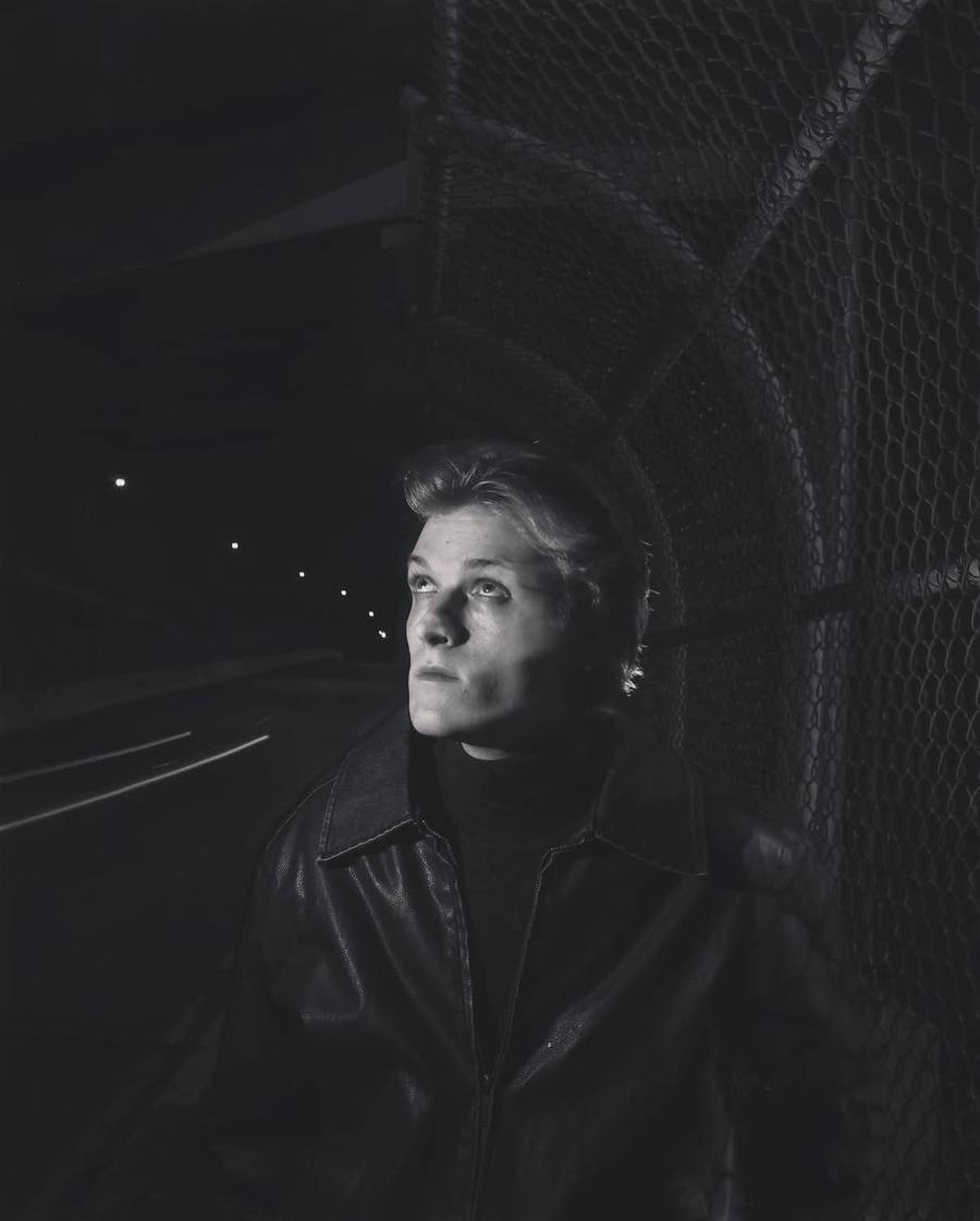 Night portrait against a chain-link fence