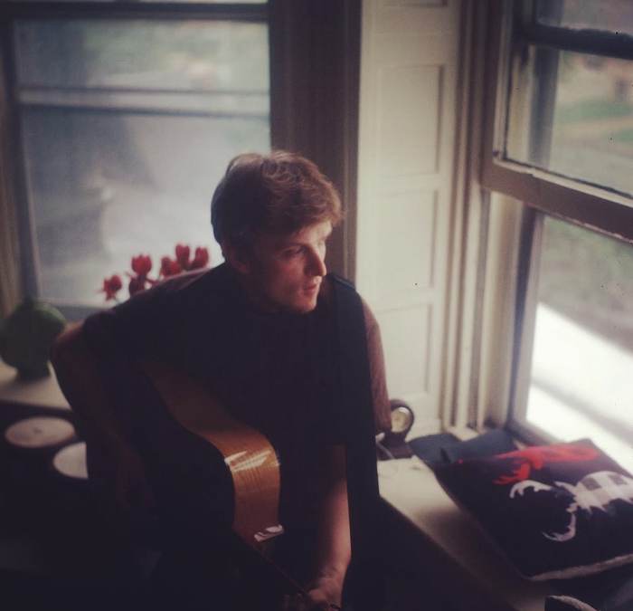Playing acoustic guitar beside a window with tulips
